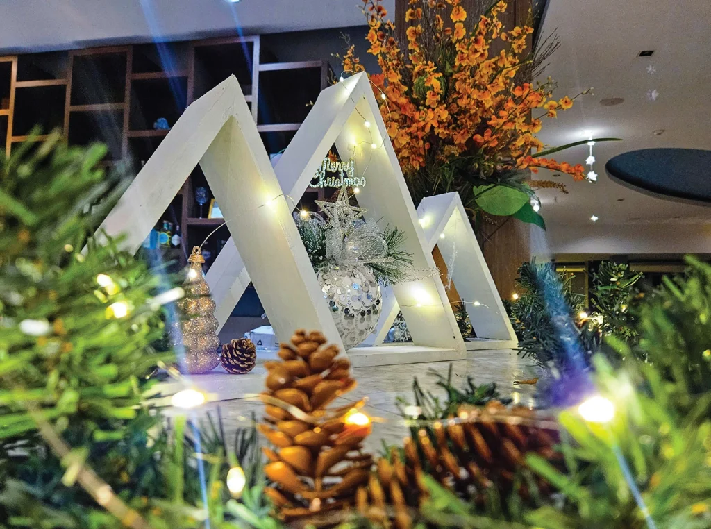 Christmas decorations with a Merry Christmas sign, pine cones and fairy lights inside Crest Resort in 2023
