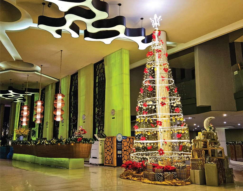 Tall Christmas tree with red flowers and gift boxes in the Crest Resort lobby during the 2023 festive season